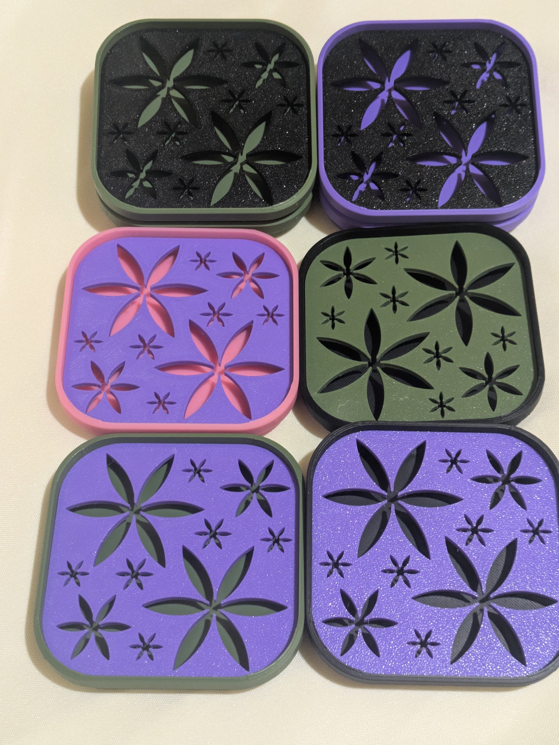 Six square 3D-printed soap trays arranged in a 2x3 grid on a light beige background. The options include black, purple, pink, and olive green pieces, each with embossed floral and starburst patterns.
